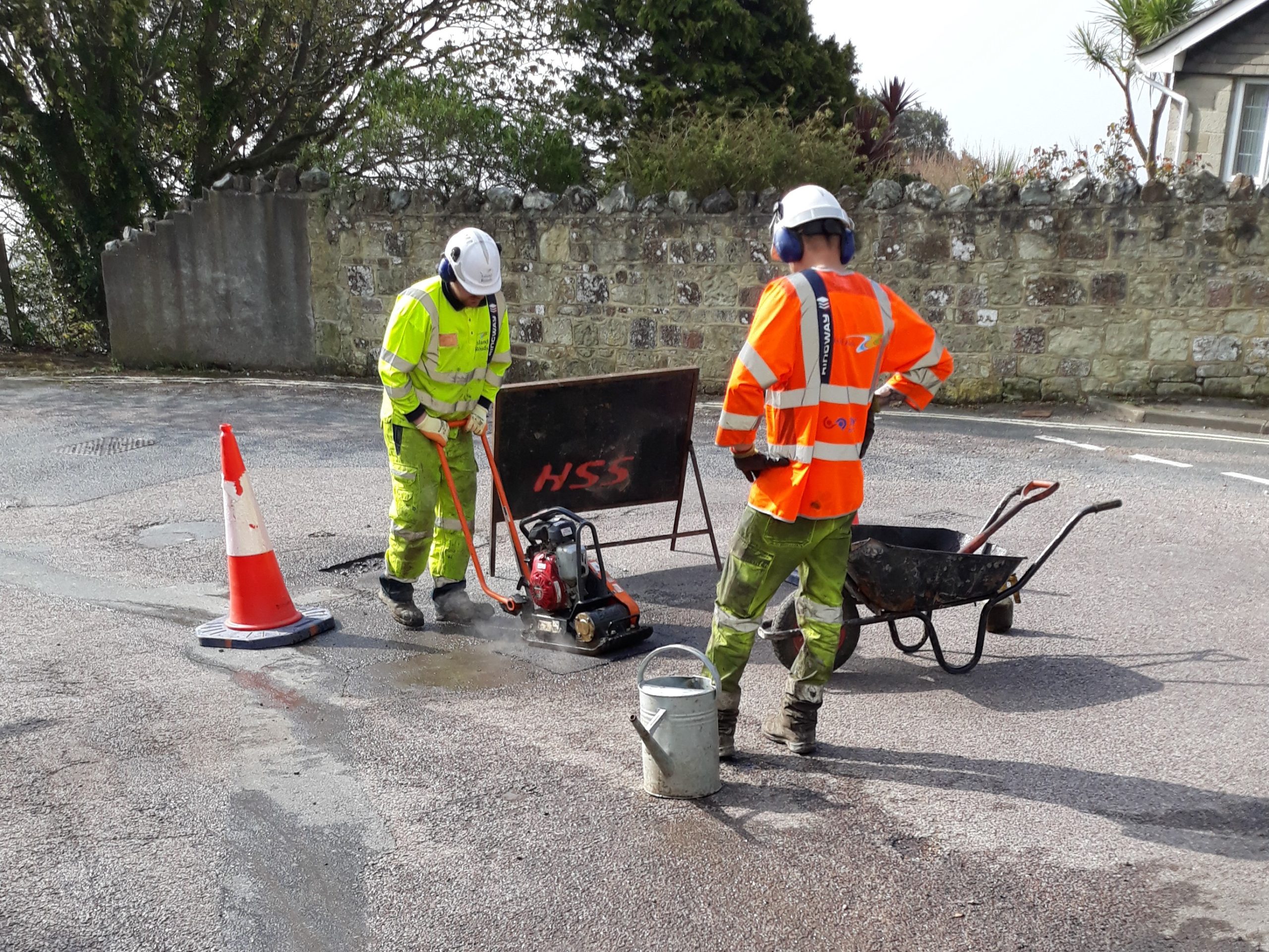 Photo showing two Island Roads operatives repairing a pot hole in the road