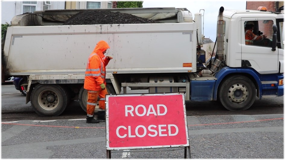 Photo showing road closed sign and vehicle and operative working in the background