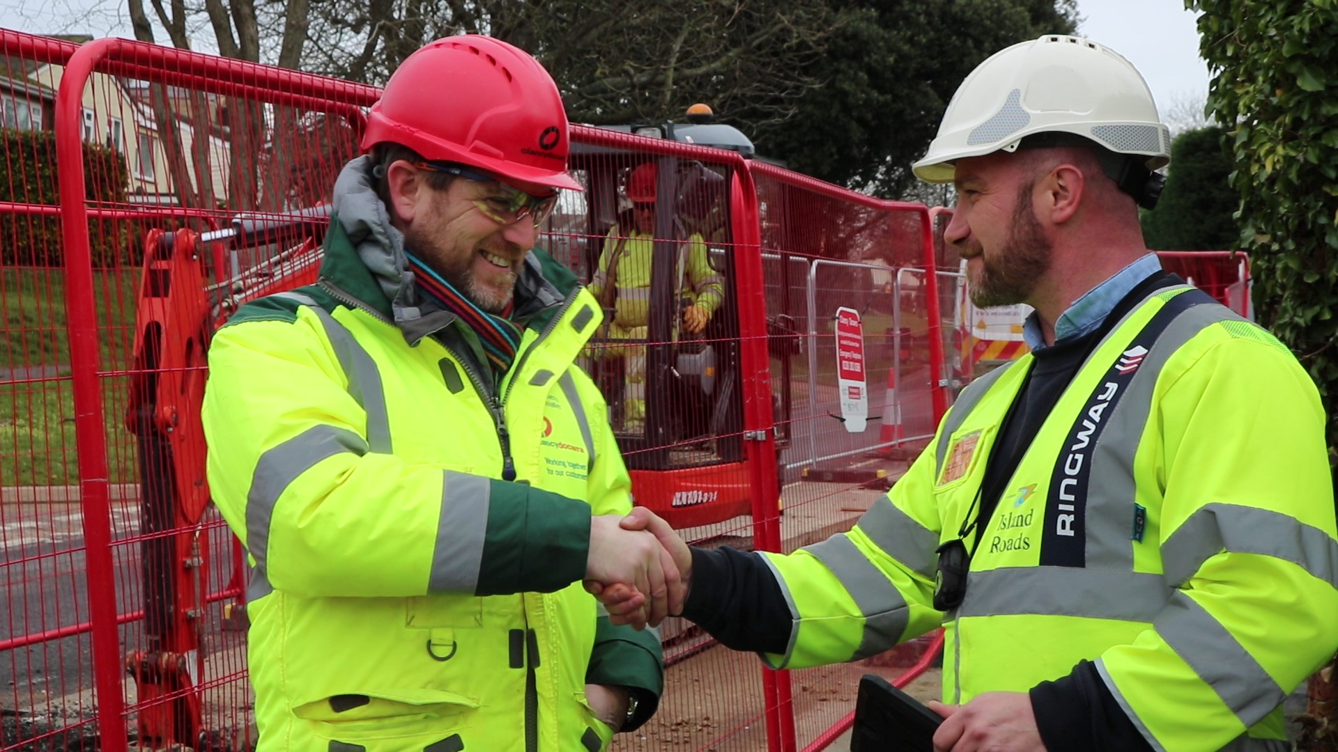 Photo showing Southern Water and Island Roads staff members shaking hands in front of work site