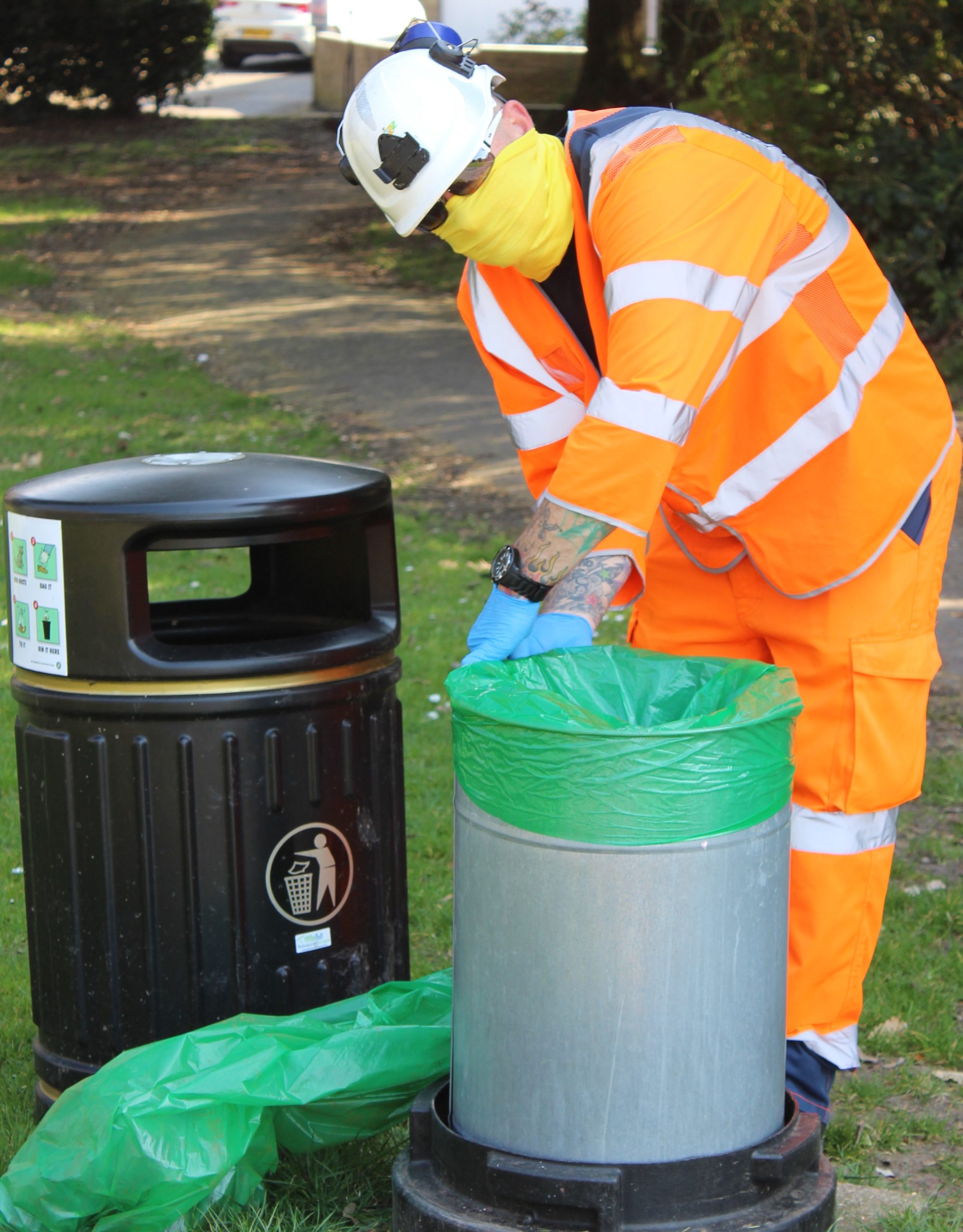 Photo showing Island Roads staff member emptying litter bins dressed in protective clothing