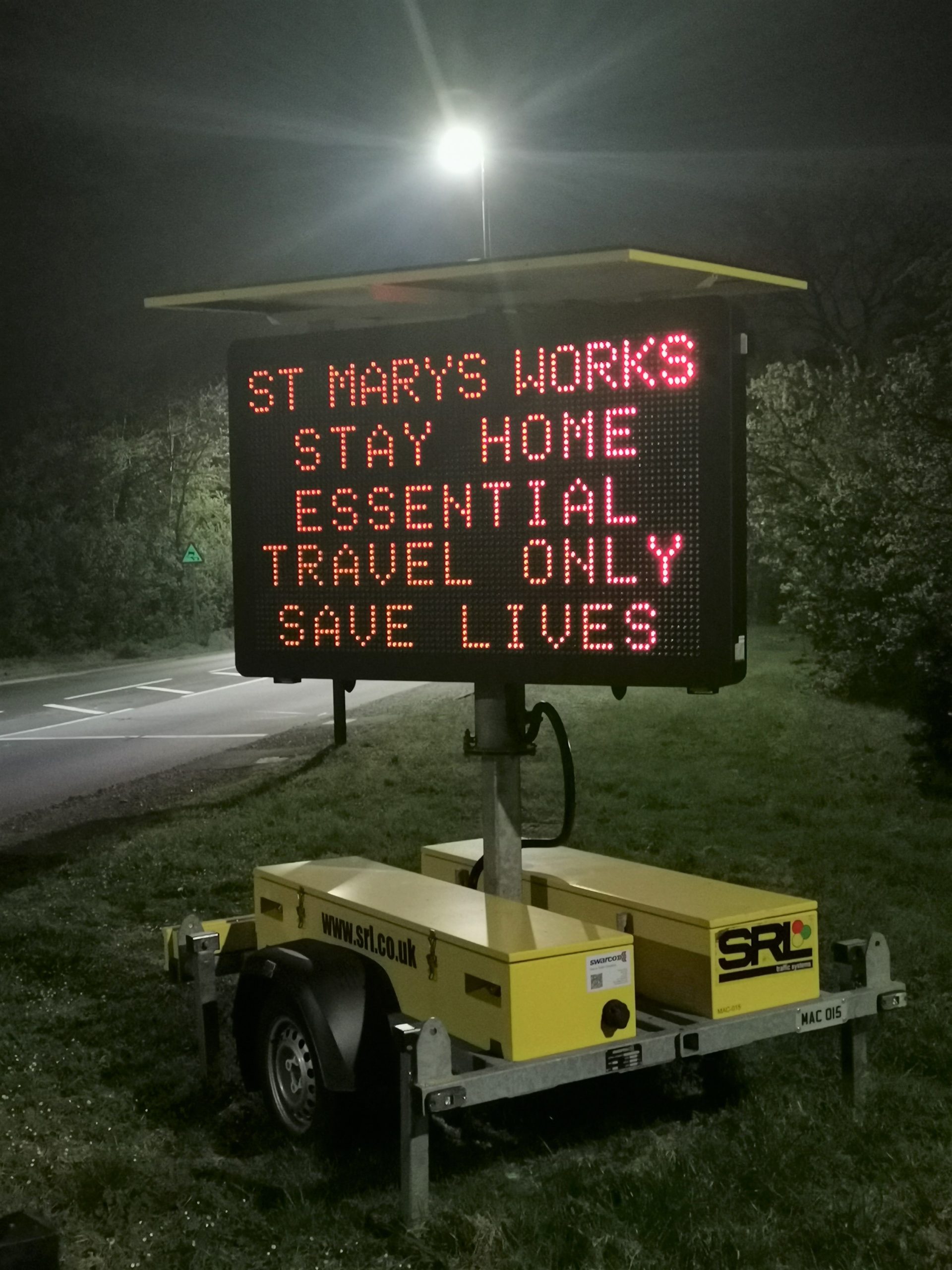 Photo showing essential health messaging on VMS signs on the roadside near St Mary's advising people to stay home, essential travel only, save lives. Photo taken at night.