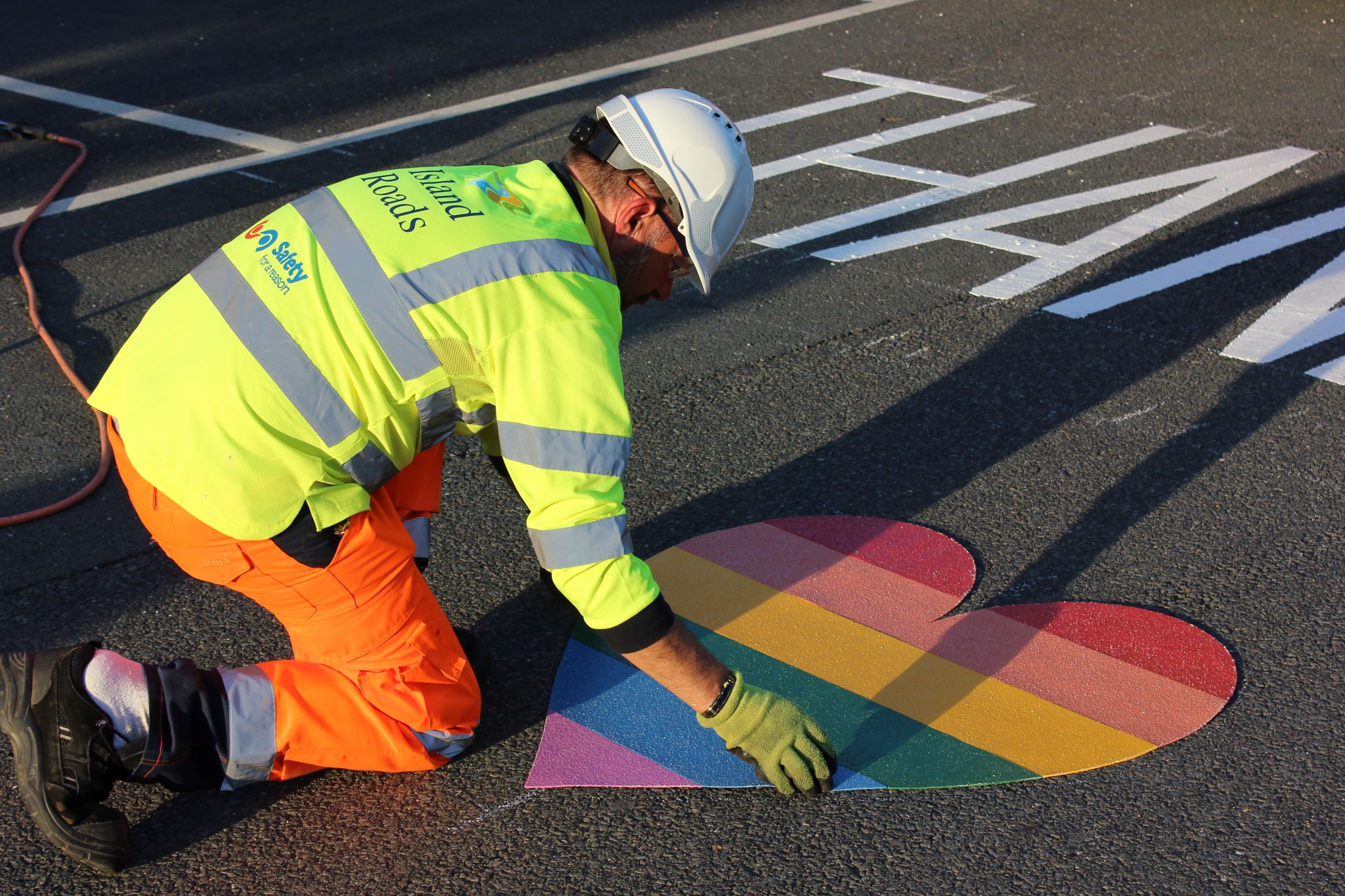 Photo showing Island Roads crew member putting painted heart in place on the Hospice grounds as a thank you to staff