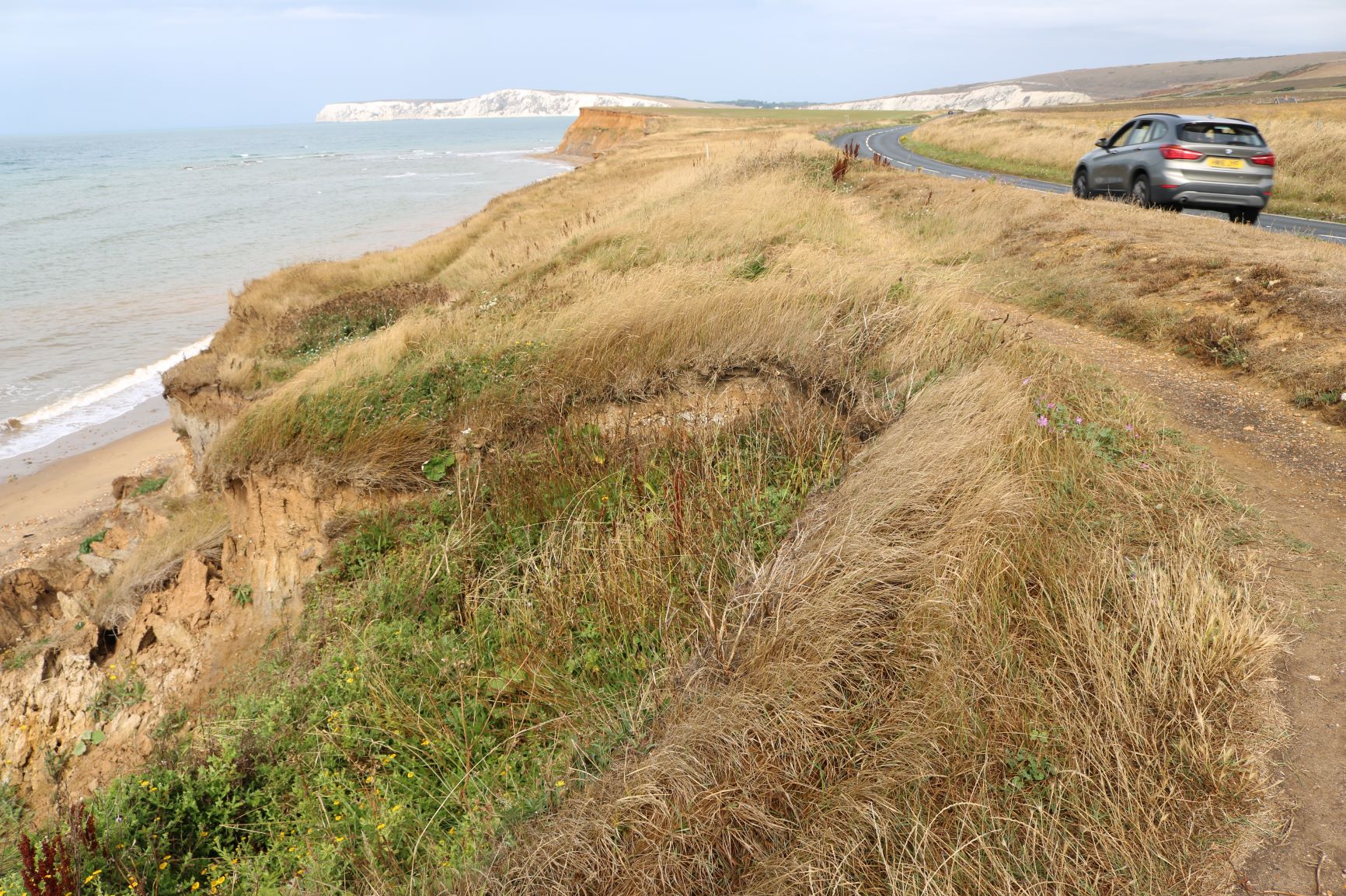 photo showing the proximity of coastal erosion to the highway at Brook, cars on road passing Chine