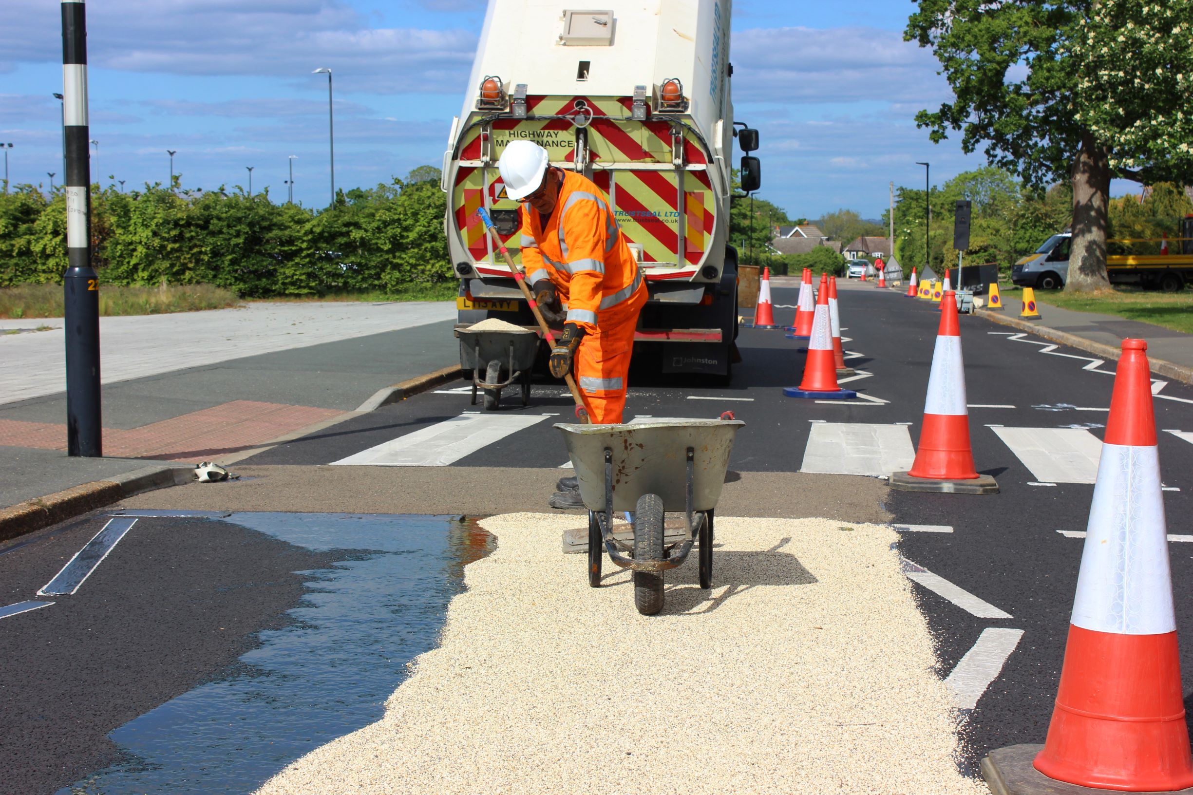 photo showing a workman and lorry laying high friction surfacing (a coarse material) in front of a pedestrian crossing