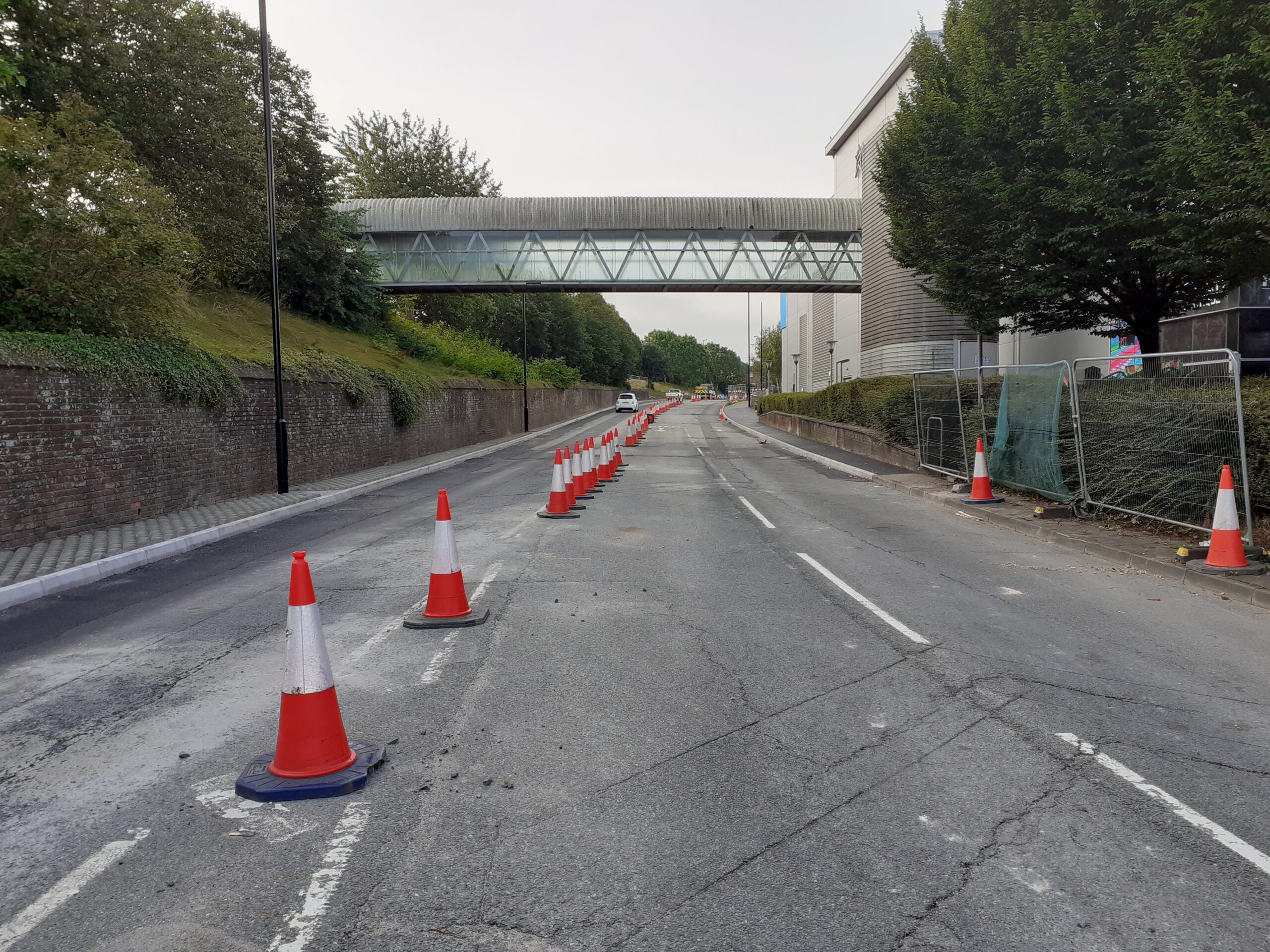 roughly surfaced road with traffic cones down the middle and safety fencing to the right hand side at St George's Way Newport