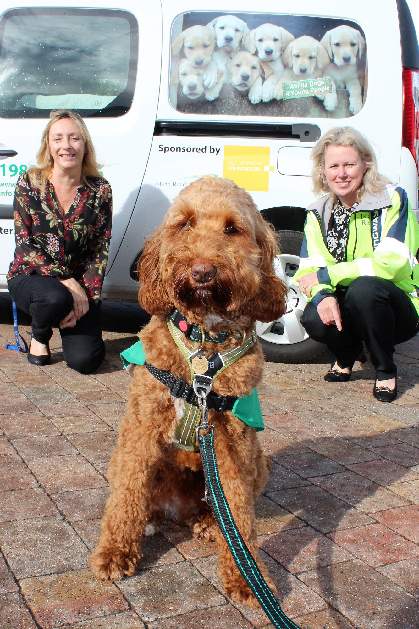 dog in front of electric vehicle with Island Road employees Samantha and Rachel