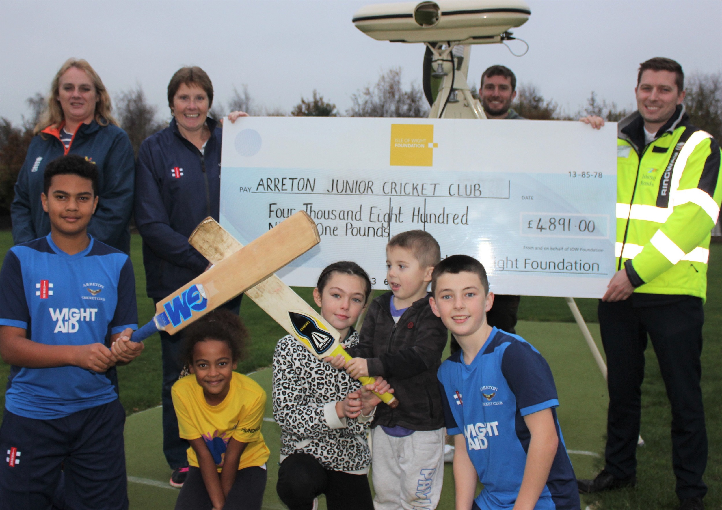 group of people holding a large cheque for £4,891 for Arreton Junior Cricket Club, children holding cricket bats in foreground