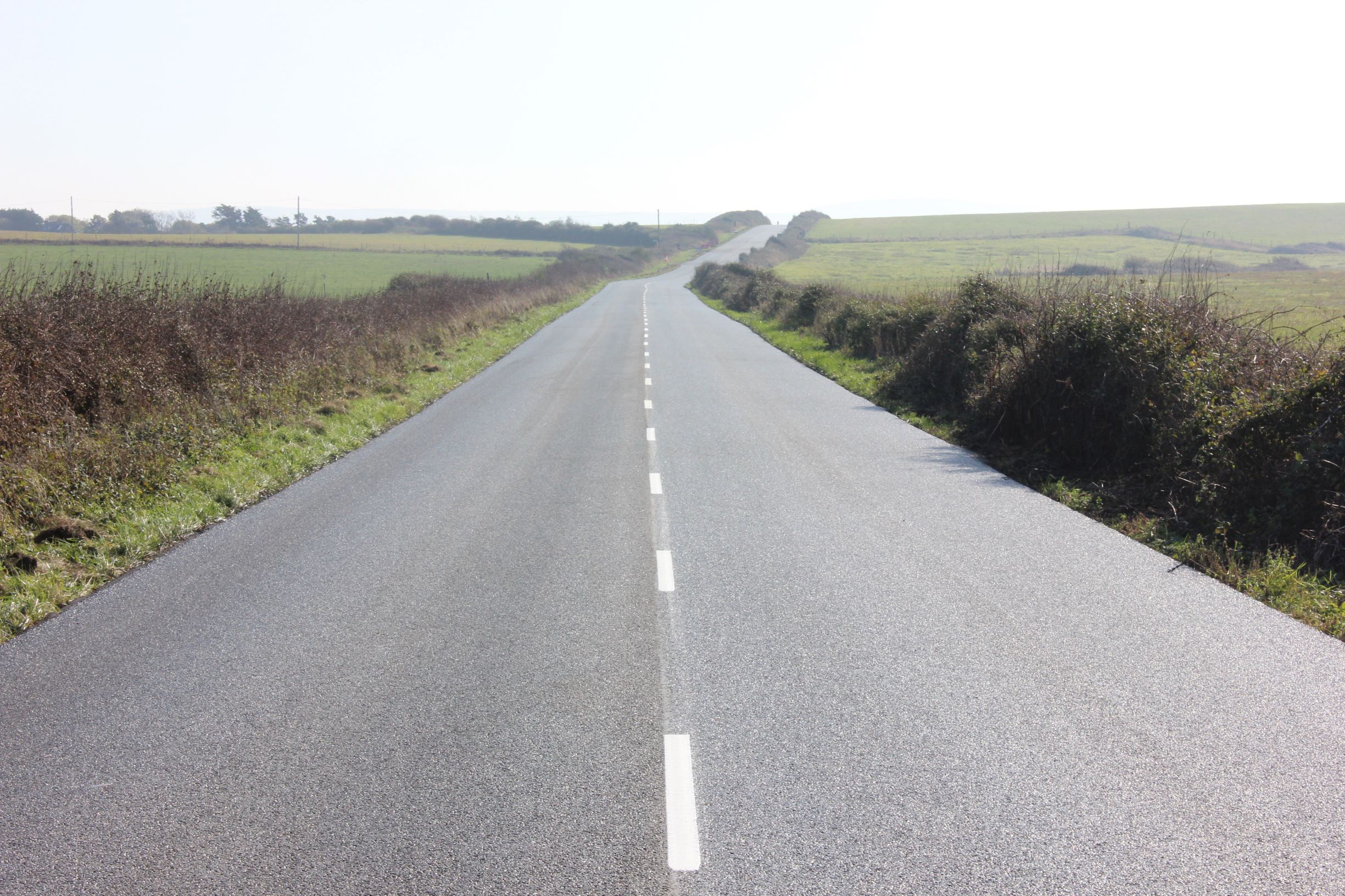 smooth lined road surface going into the distance with fields either side