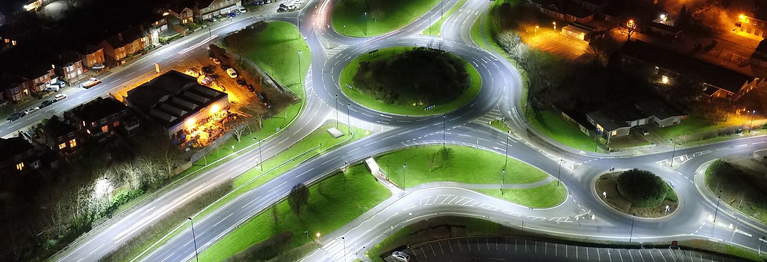 aerial view of two roundabouts at night lit up by street lamps