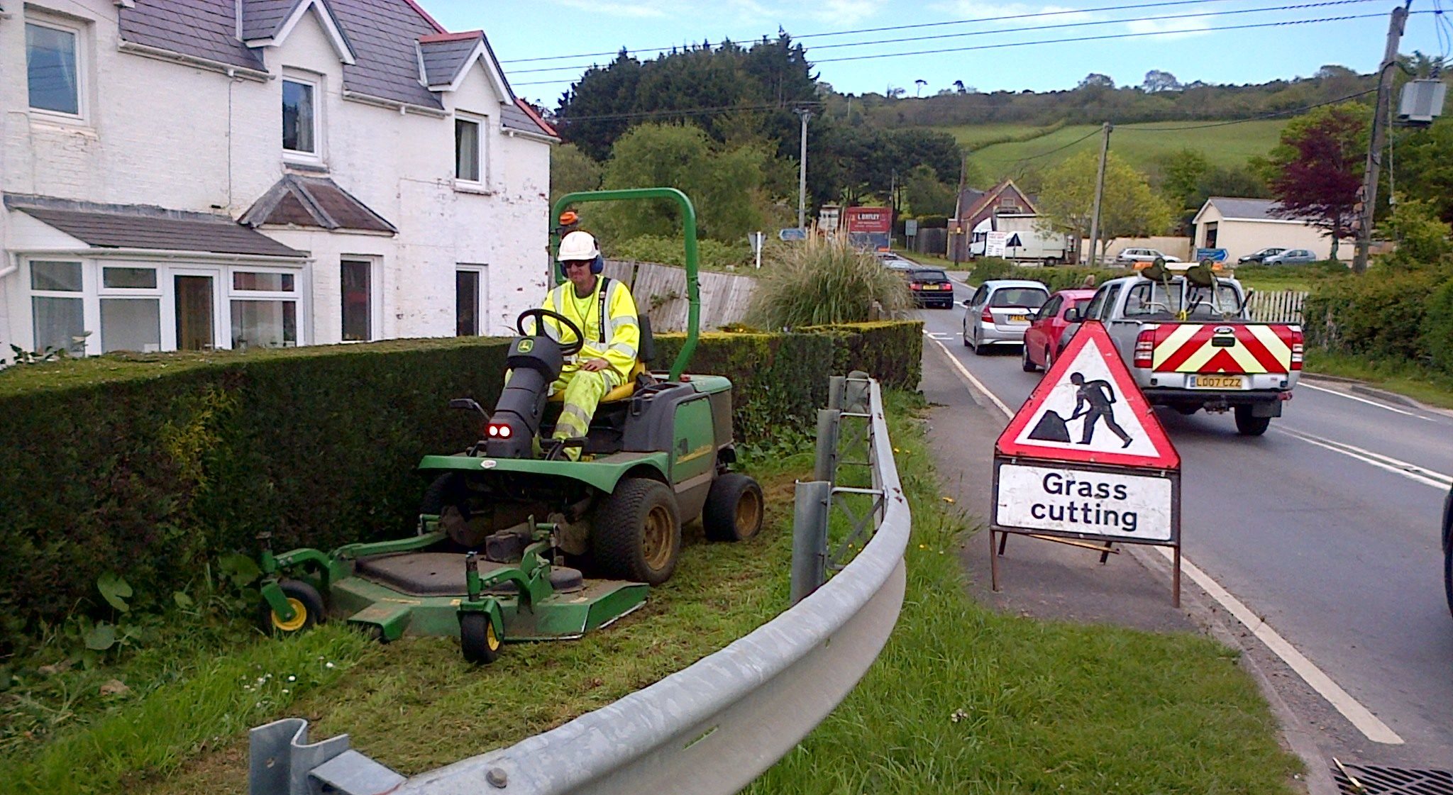 Photo showing grass being cut using a ride on mower along the verge