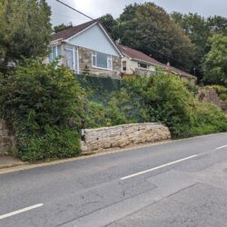 section of road, bank/verge is shored up with a 'wall' of sandbags