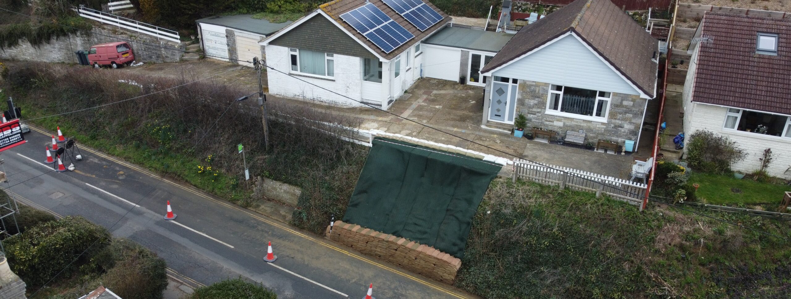 section of highway in Wroxall showing where a landslip has been temporarily repaired with sandbags prior to full repair