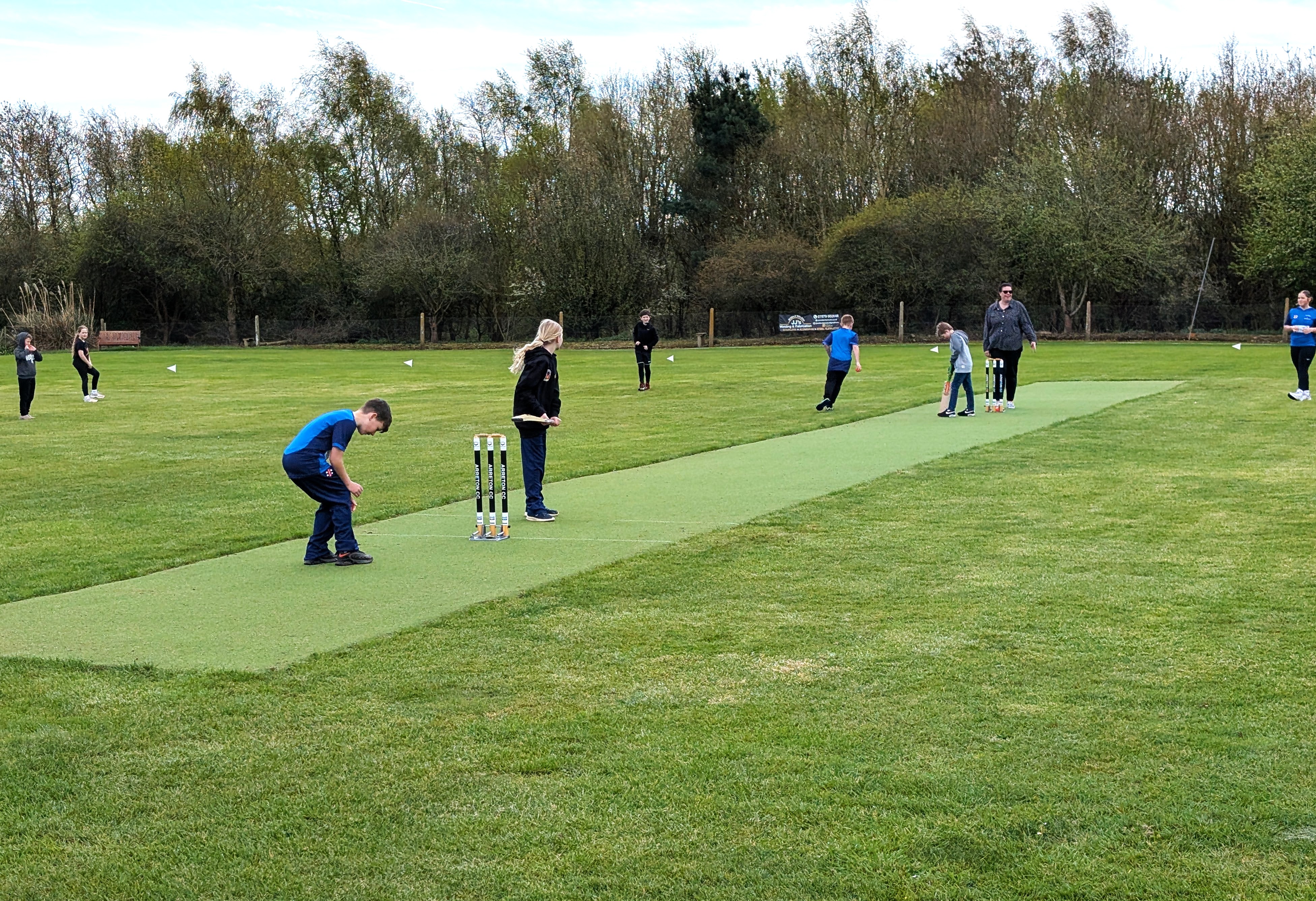 children playing cricket on green pitch